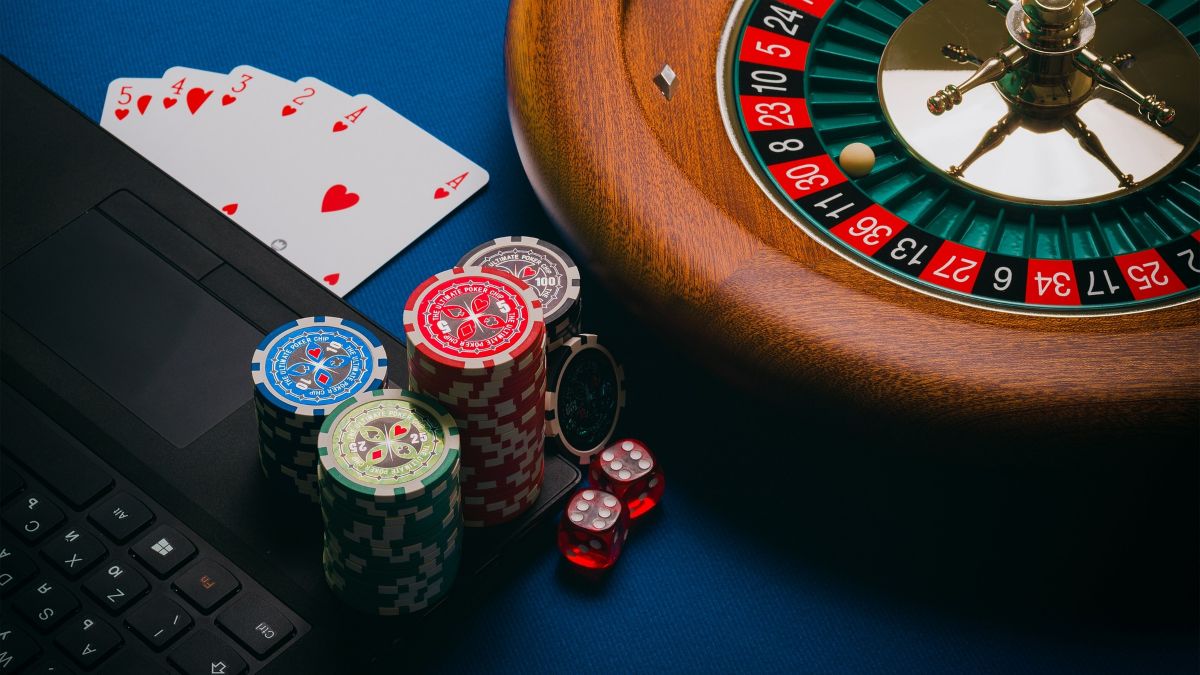 Roulette wheel with casino chips stacked on laptop, with straight flush