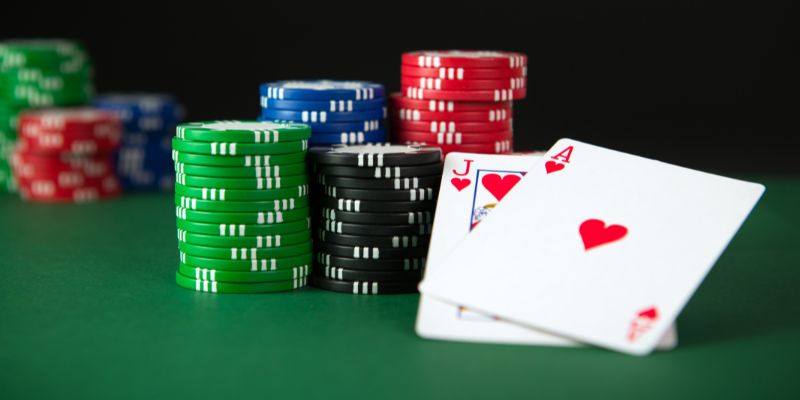 Untitled design (10) Stacked casino chips with jack and ace of hearts on green casino table