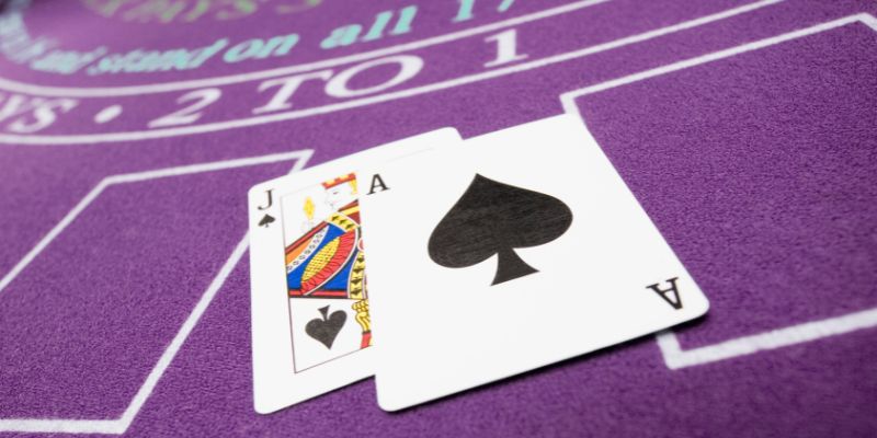 Untitled design (9) Jack and ace of spades laying face up on purple blackjack table