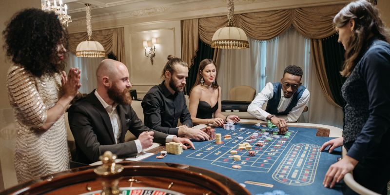 Untitled design (12) People sitting around roulette table making bets