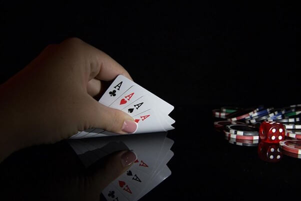 Full suite of Aces lifted by hand, with casino chips on the right