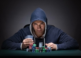 an ominous looking man wearing a hoody at a poker table