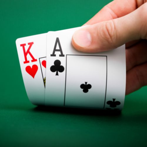 a person holding up an ace and a king on a blackjack table